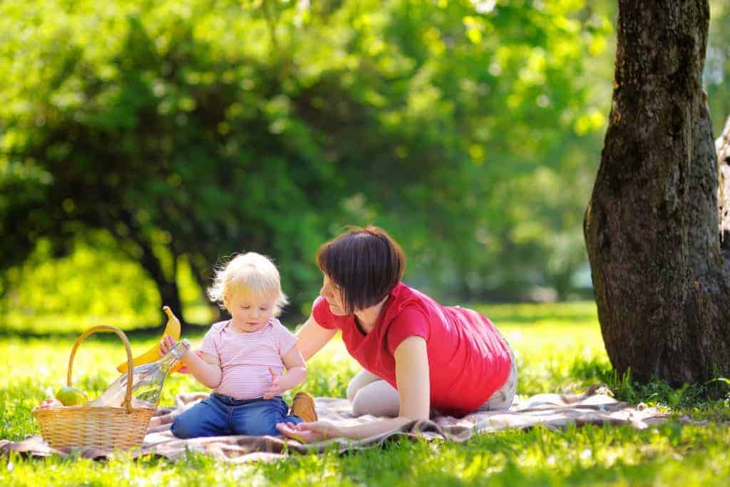 Middle aged woman and her little grandson in sunny park