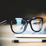 Glasses on laptop with pen, close up