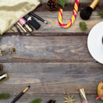 Cosmetics for make-up and Christmas decorations on a wooden background. Flat lay
